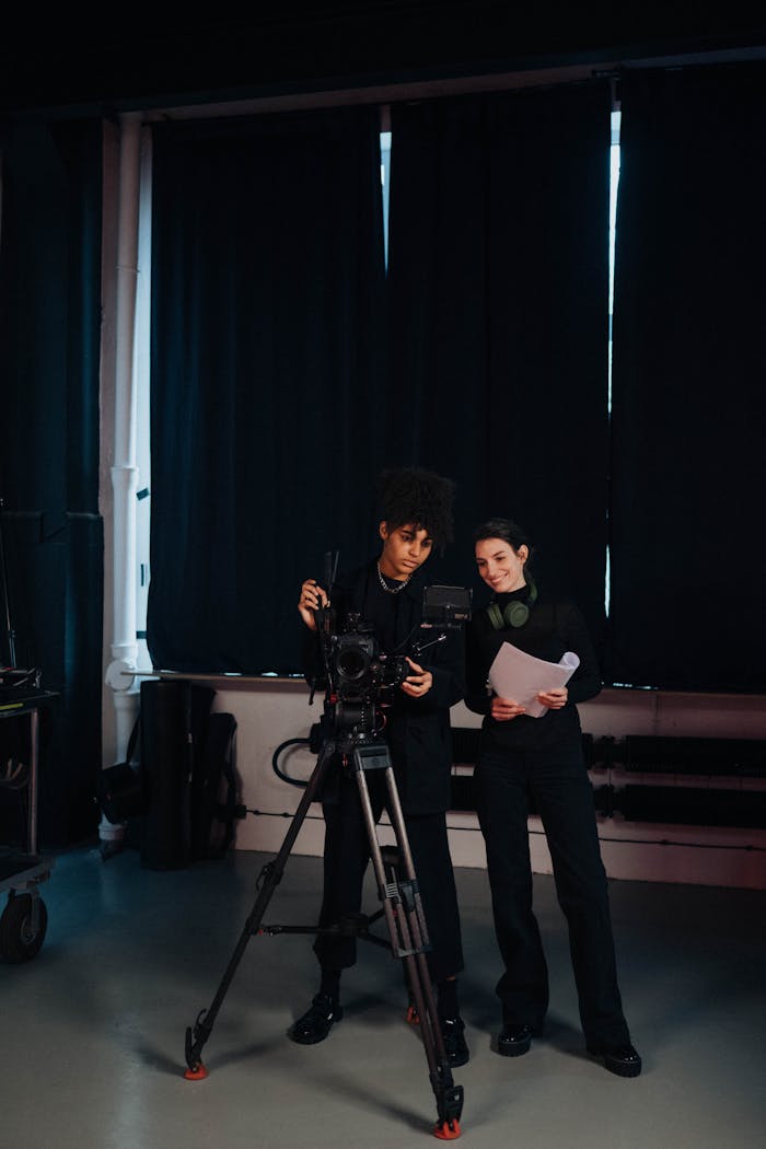 Two crew members in a studio setting working on a film production with camera equipment.